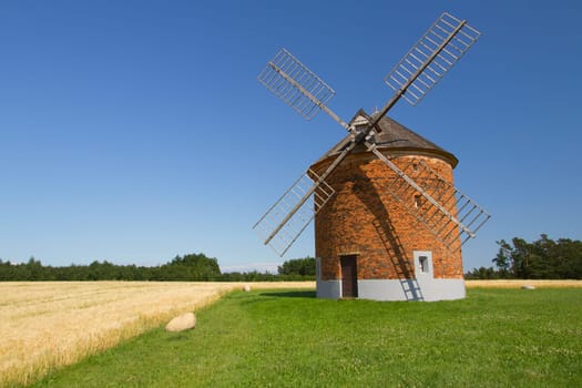 Brick windmill in a field of corn. Blue sky in the background. (Chvalkovice, Czech Republic)