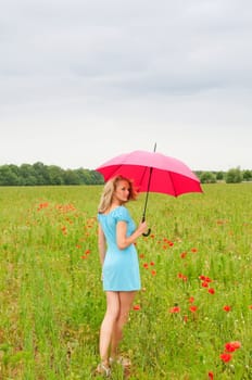 Woman with umbrella in poppy field