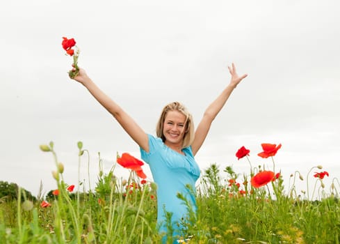 Young woman cheering in poppy field