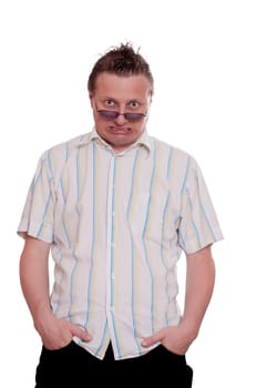 European man looks anxiously over his glasses and has his hands in his trouser pockets