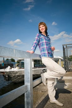 Full length portrait of a young brunette woman leaning on a railing and excursion steamers in blurred background