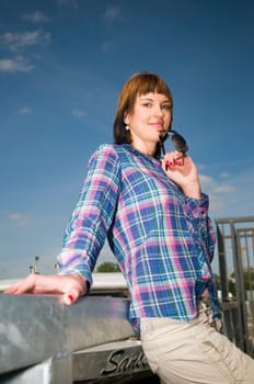 Upper body portrait of a young brunette woman fishing on a railing and excursion steamers in blurred background