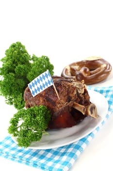 a grilled knuckle with pretzels and parsley against a white background