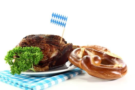 a grilled knuckle with pretzels and parsley against a white background