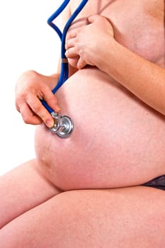 Pregnant woman listening through a stethoscope beating hearts of their baby