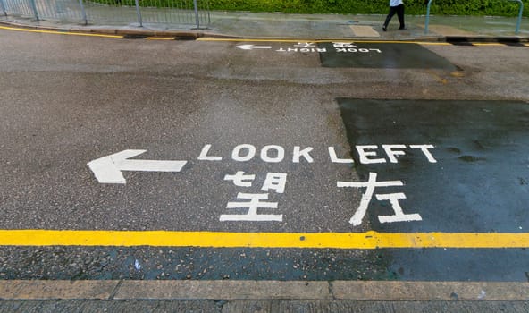 "look left"" sign on a street in hong kong, advising safety for pedestrians"