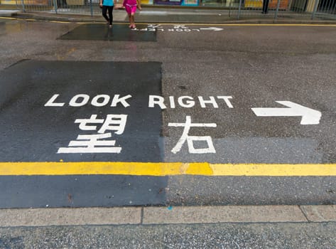 "look right"" sign on a street in hong kong, advising safety for pedestrians"