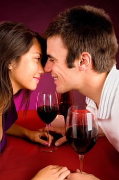 Couple sitting at a table drinking wine and getting close.