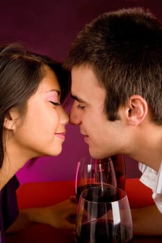 Couple sitting at a table drinking wine and getting close.