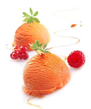 Balls of exotic tropical mango ice-cream garnished with berries on a white studio background
