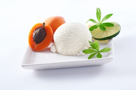 Serving of tangy refreshing lime sorbet icecream with apricots on a square porcelain plate