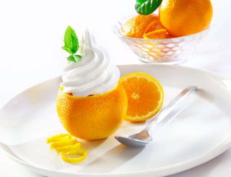 Serving of refreshing tropical dessert with a sliced orange topped with vanilla softserve icecream on a plate