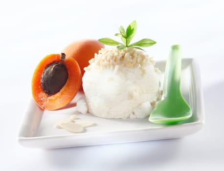 Sorbet icecream with almond topping and apricots served on a square white plate