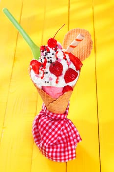 Gourmet ice-cream cone with ripe red strawberries and wafer biscuits wrapped in a checkered red and white napkin