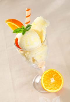 Colourful tropical icecream dessert with fresh orange slices and a spiral wafer biscuit