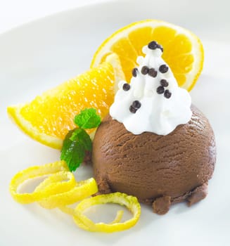 Gourmet chocolate icecream dessert topped with whipped cream and served with orange slices and zest