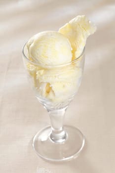 High angle view of a glass filled with delicious creamy vanilla ice-cream on a white background