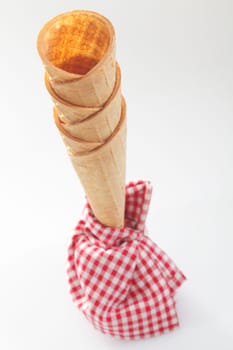 High angle view of a stack of crisp empty ice-cream cones with a red and white checkered napkin