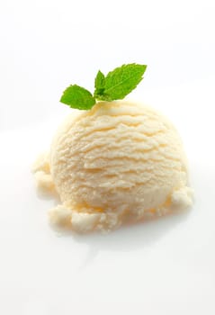 Scoop of vanilla ice-cream topped with fresh green mint leaves on a white backgound