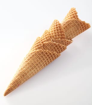 Stack of crisp golden waffle cones with the traditional indented pattern for use with icecream