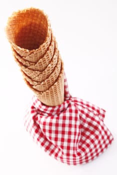 Stacked tower of empty ice-cream cones with a colourful rustic red and white checkered napkin