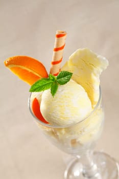Creamy tropical icecream dessert with sweet orange slices and a colourful striped wafer biscuit