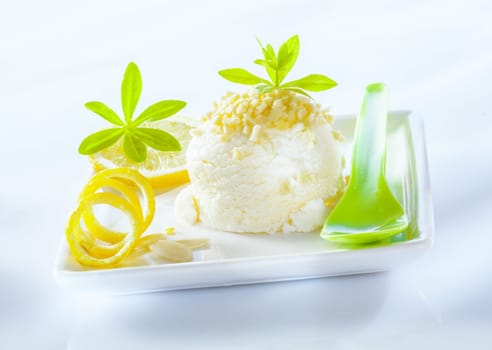 Refreshing sour lemon sorbet dessert served with coiled lemon zest on a square porcelain platter