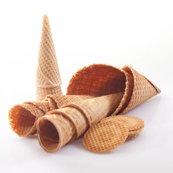 Assortment of icecream cones and cornets in different shapes and sizes together with wafer biscuits on a white background