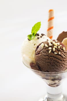Balls of chocolate and vanilla ice-cream topped with chopped nuts in a conical glass parfait dish