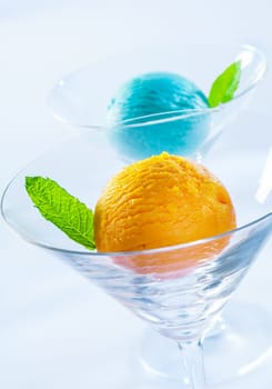 Yellow and blue ice cream balls decorated with mint leaves