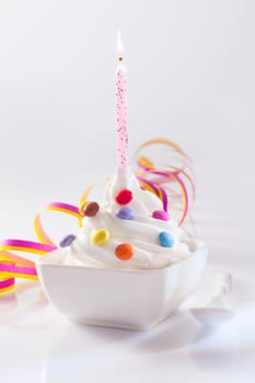 Festive and Birthday Dessert with candle. Frozen Yogurt served with sweet candies topping and paper streamer for birthday concepts