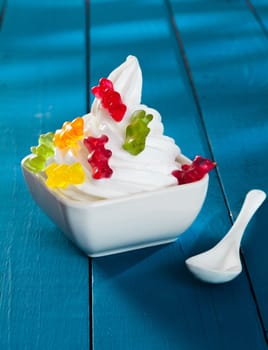 Funny Frozen Yogurt with gummi bears as topping on a wooden blue background
