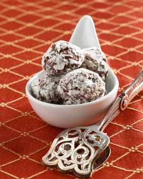 Handmade luxury chocolates or truffles in a procelain spatula with silver tongs for serving