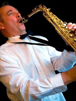 A man is playing alto saxophone on a black background.