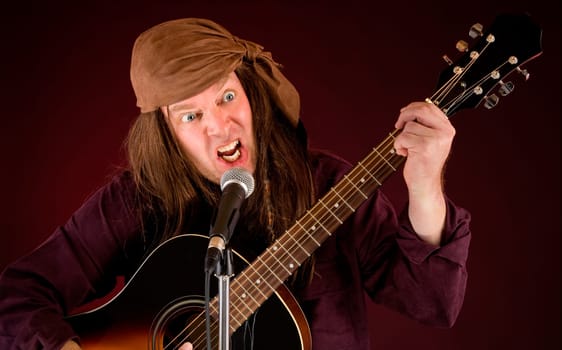 A man is madly playing acoustic guitar and singing.