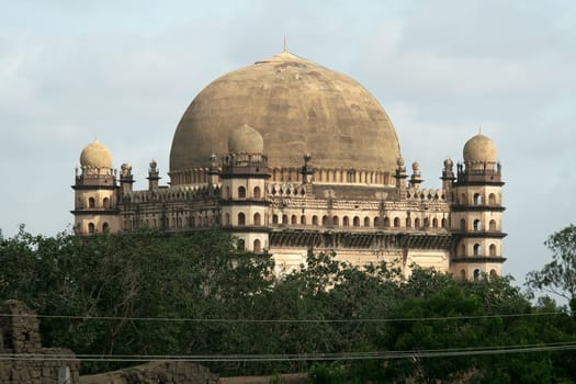 Greenery partially obscuring magnificent Gol Gumbaz at Bijapur, Karnataka, India, Asia
