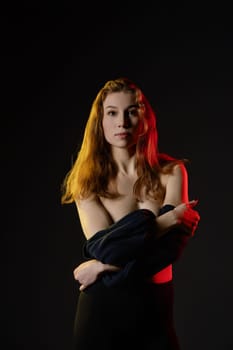 A woman elegantly dances, her beauty highlighted by soft lighting against a dark background. Her confident pose exudes artistic expression.