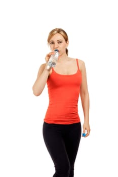 Blonde young fitness woman drinking water against white background