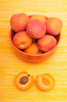 Apricot with apricot kernel next to a bowl in portrait format
