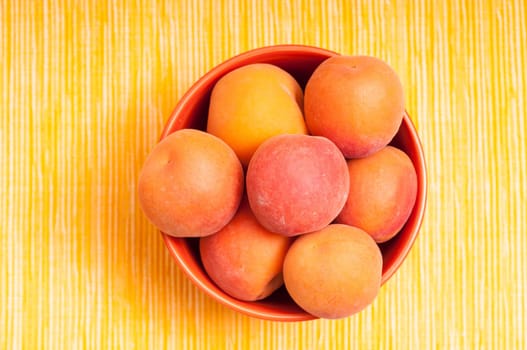 Apricots in a bowl against yellow background