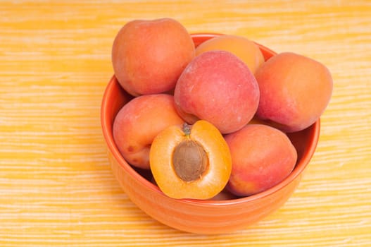 Apricots in a bowl against a yellow background