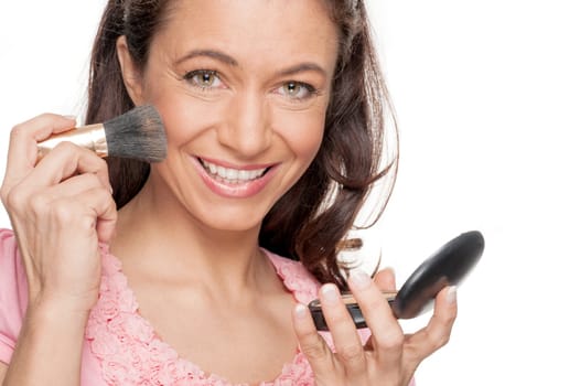 Smiling woman in front of white studio background doing make-up