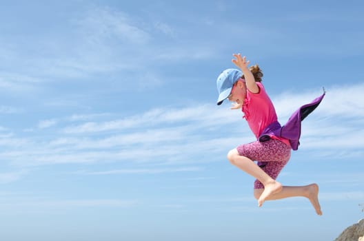 Toddler jumping in front of blue sky