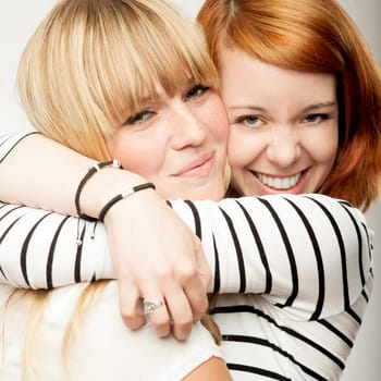 red and blond haired girls friends laughing and hug