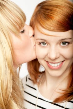 blond girl give red haired girl kiss and smile
