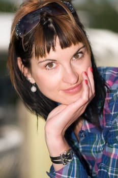 Head and shoulders portrait of a young brunette woman wearing sunglasses and looking directly at the camera