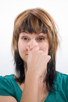 Head and shoulders shot of a young woman looking into the camera,holding her nose
