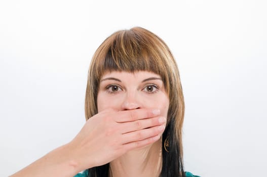 Head and shoulders view of a young woman looking at the camera and covering her mouth  Gesture: "don't say anything"""