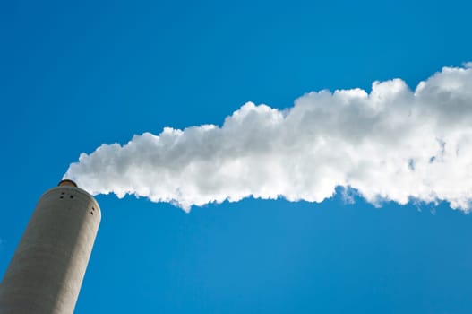 smoking industrial chimney against a blue sky