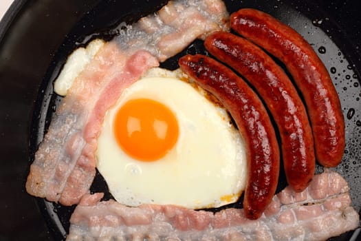 Fried egg and bacon in a frying pan.